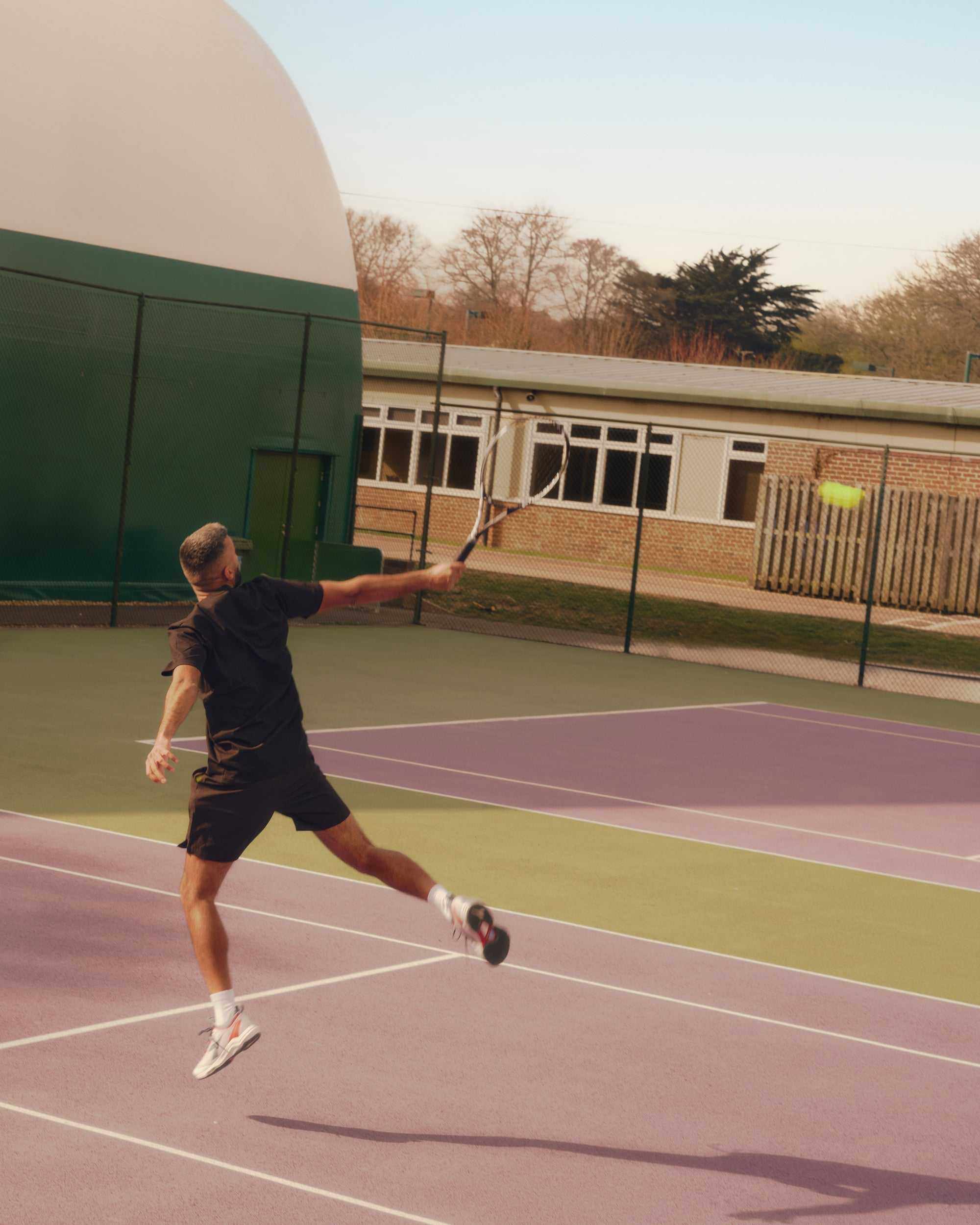 male tennis player performing a backhand shot on outdoor court during tennis footwork drills session