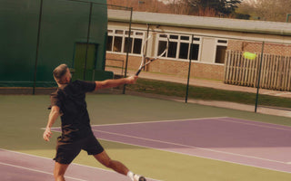 Male tennis player performing a jumping forehand shot on an outdoor court during training session