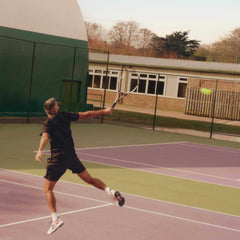 Male tennis player hitting a serve on outdoor court during professional tennis circuit