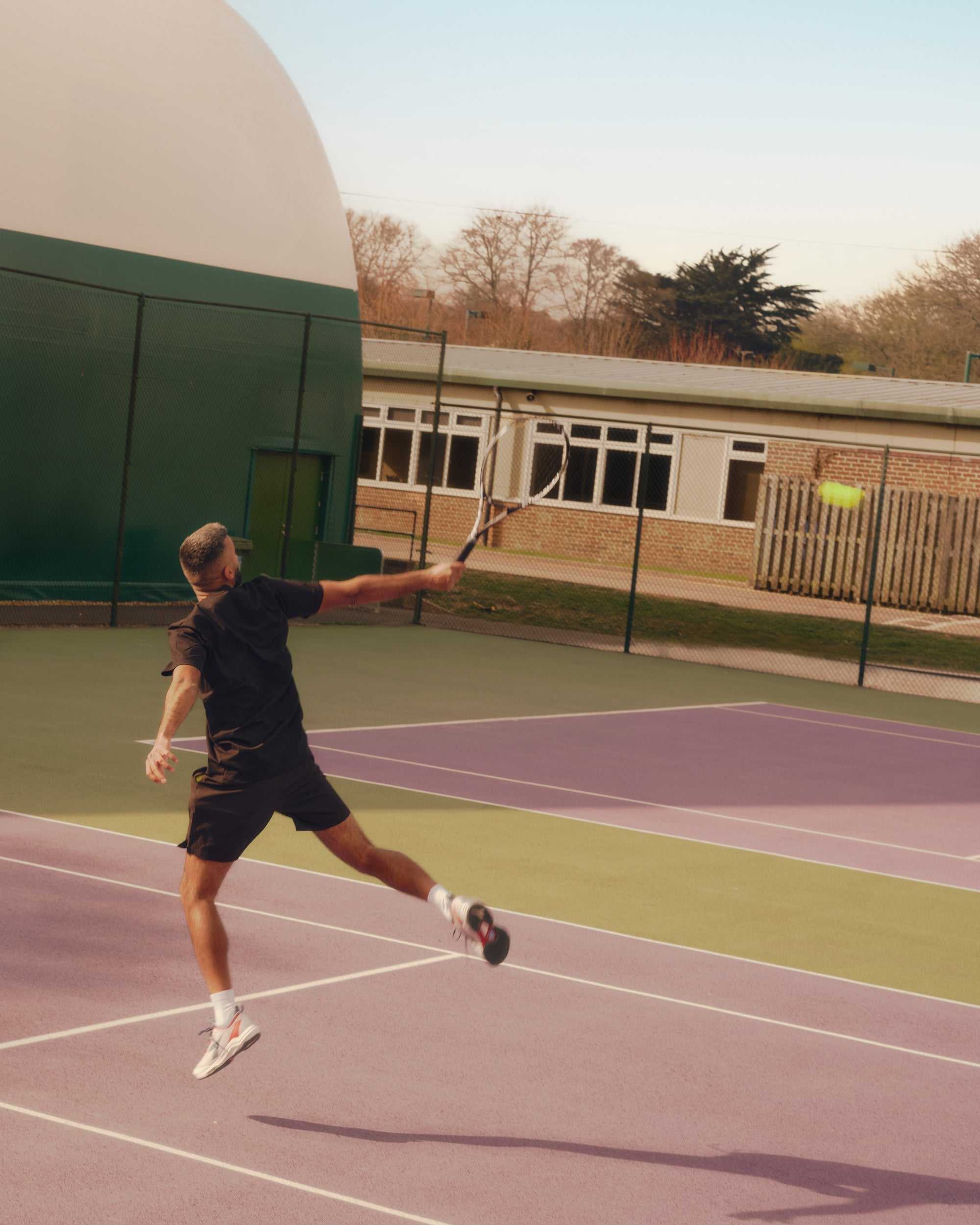 male tennis player practicing serve on outdoor court at professional tennis circuit facility