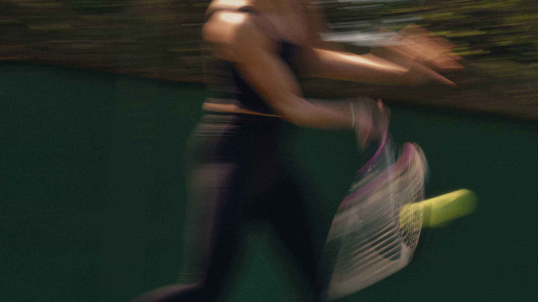 Blurred action shot of a tennis player demonstrating forehand technique with racquet hitting a tennis ball