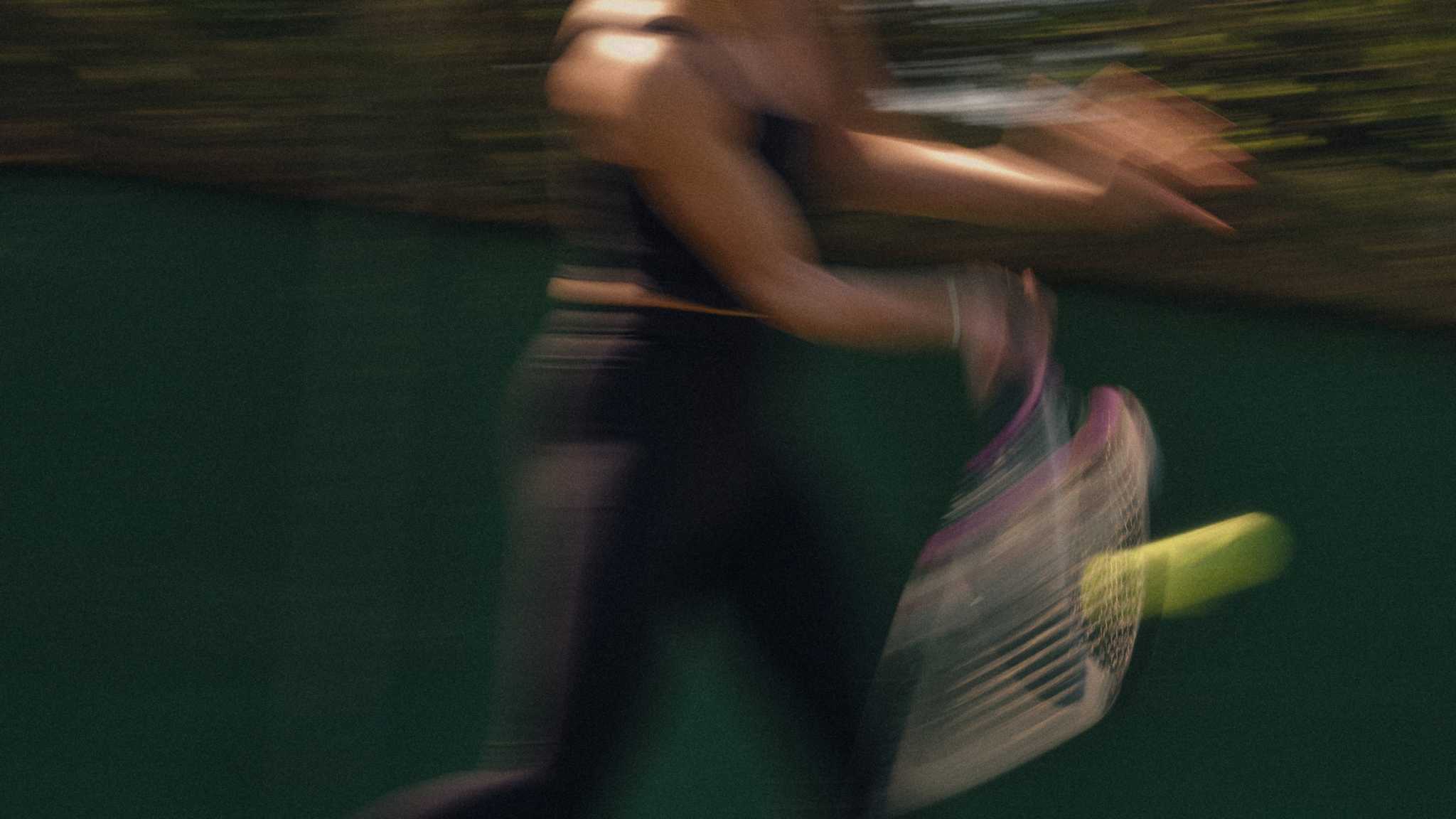 Blurred tennis player executing a forehand shot with racket and ball in motion on outdoor court, demonstrating forehand technique.