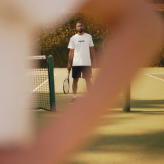 Male beginner tennis player standing on court holding racquet during tennis lessons for beginners session