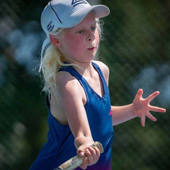 young girl playing tennis with junior size tennis racket outdoors on court