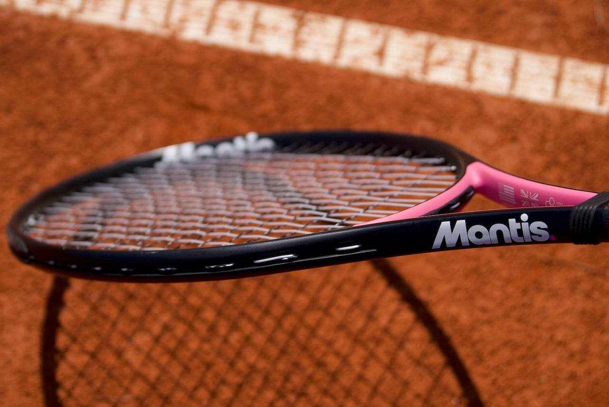 Close-up of a Mantis tennis racket with focus on the strings on a clay tennis court, promoting the best tennis strings for spin.