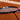 Close-up of a Mantis tennis racquet with black and pink frame on a clay court, highlighting the strings for spin performance.