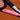 Close-up of Mantis tennis racket frame highlighting design and development origins with USA and UK flags and high modulus carbon label against a tennis court background.
