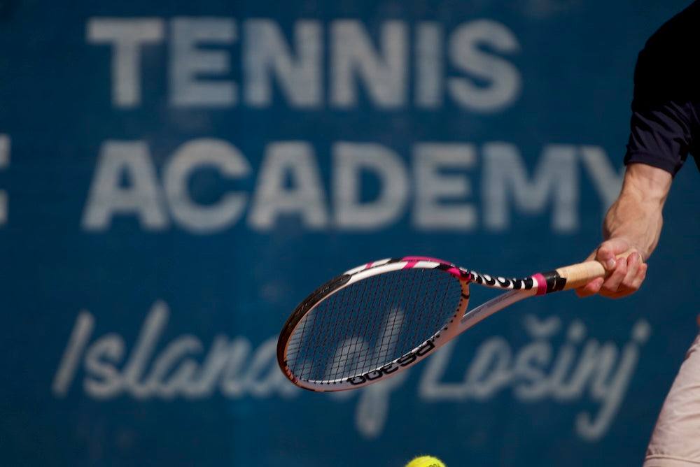 Tennis player holding racquet at tennis academy court, learning to play tennis beginner guide