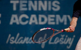 Tennis player preparing to hit ball with racquet at tennis academy court for learning to play tennis beginners