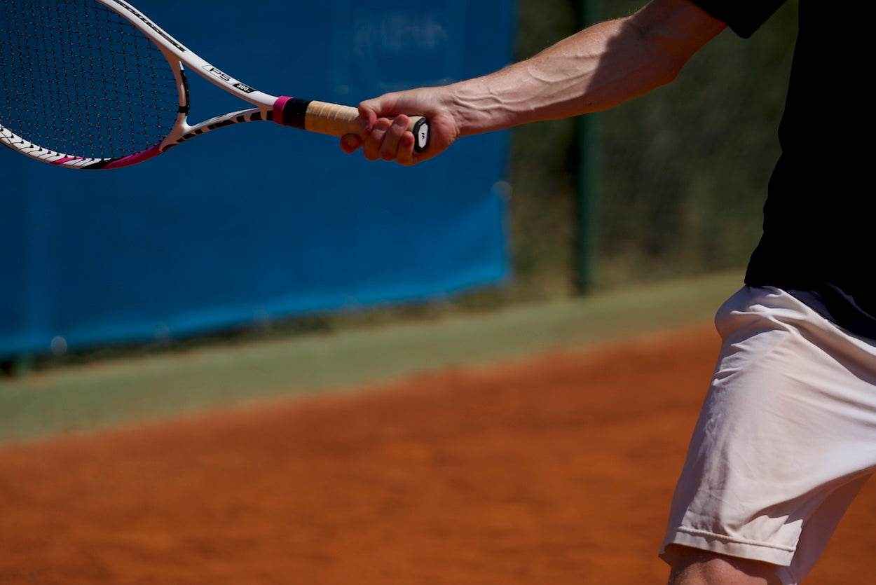 Tennis player swinging racquet focusing on forearm and elbow to prevent tennis elbow injury
