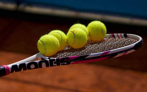 Mantis tennis racket with five yellow tennis balls on clay court background for comparing tennis rackets review and selection guide