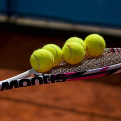 Tennis racket with yellow balls on clay court representing UK amateur tennis scene and equipment guidance