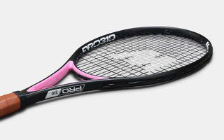 Black and pink tennis racket with brown grip and tightly woven strings suitable for use with a tennis racket dampener.