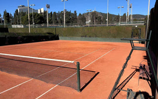 Empty clay tennis court with net and umpire chair ready for tennis lessons for adults