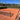 Empty clay tennis court with net and chair umpire stand under clear sky, ideal for tennis lessons for adults