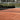 Empty clay tennis court with net and surrounding greenery under daylight for expert tennis instruction guide