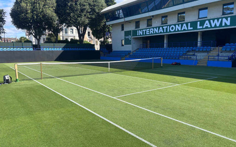 empty international lawn tennis court with net under blue sky and trees for online tennis instruction training