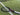 Mantis beginner tennis racket with black and pink frame lying on artificial turf near net line