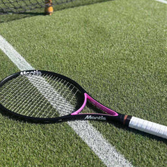 Mantis beginner tennis racket with black and pink frame lying on artificial turf near net line