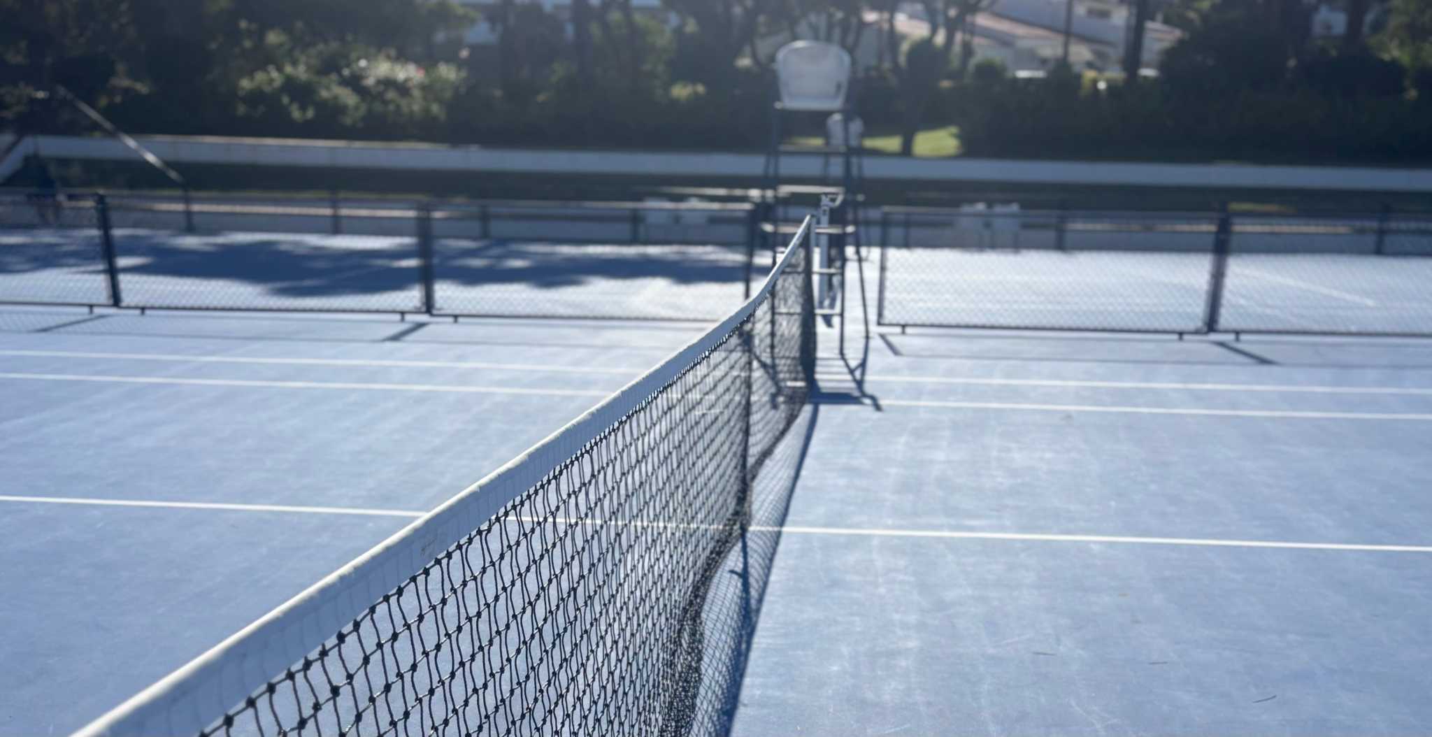 empty tennis court with net and clear court lines on sunny day
