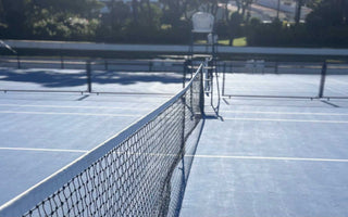 empty tennis court with net and clear court lines on sunny day