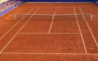 Clay tennis court with official tennis court size markings and net in place