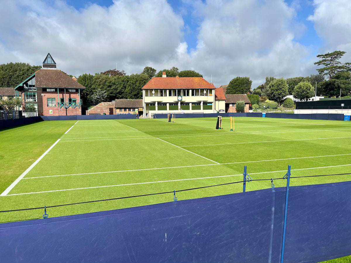 tennis court with green grass and clear sky illustrating tennis rules for beginners guide