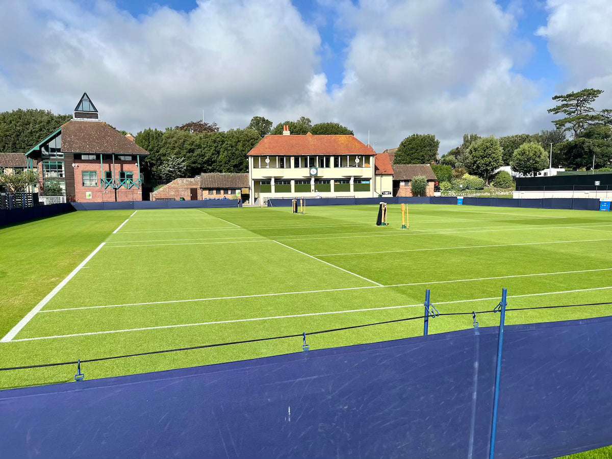 Tennis court with clear boundary lines and buildings in background illustrating tennis rules for beginners