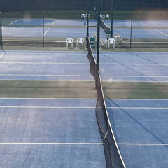 blue hard tennis court surface with net and fencing under sunlight at outdoor facility