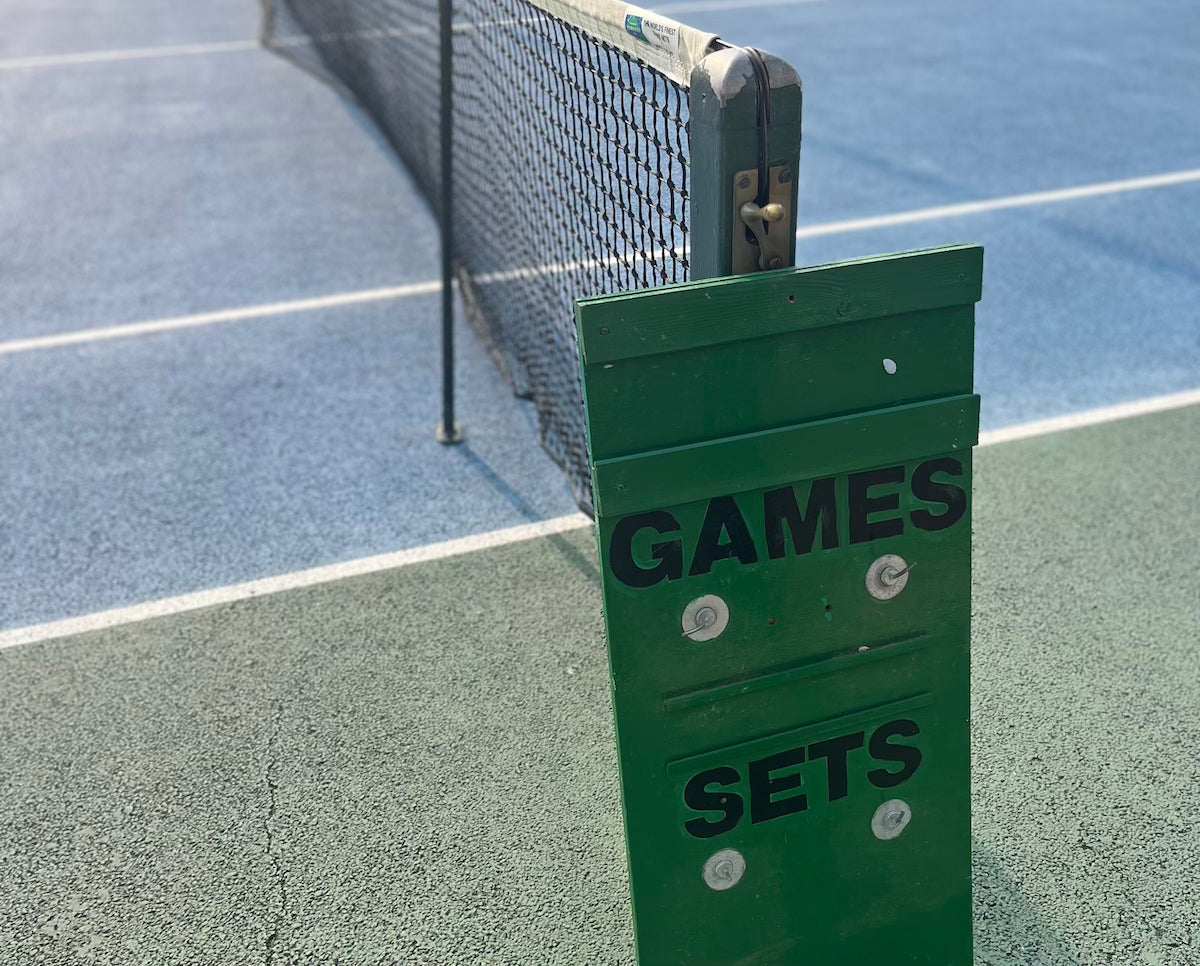 Tennis court net with scoreboard showing games and sets counters in green panel