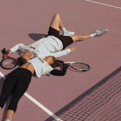 two tennis players lying on court with rackets emphasizing sports injuries prevention and safe play