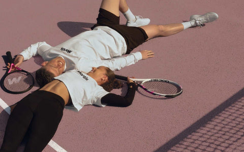 two tennis players lying on court with rackets emphasizing sports injuries prevention and safe play