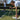 Woman tying shoelaces on tennis court holding a racket, man practicing in the background during tennis training session