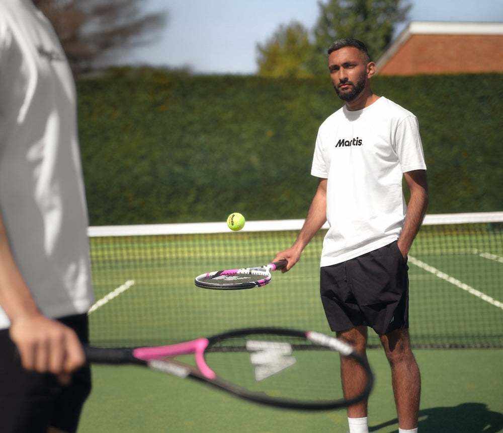Man playing tennis with a Mantis tennis racket designed for spin on outdoor court