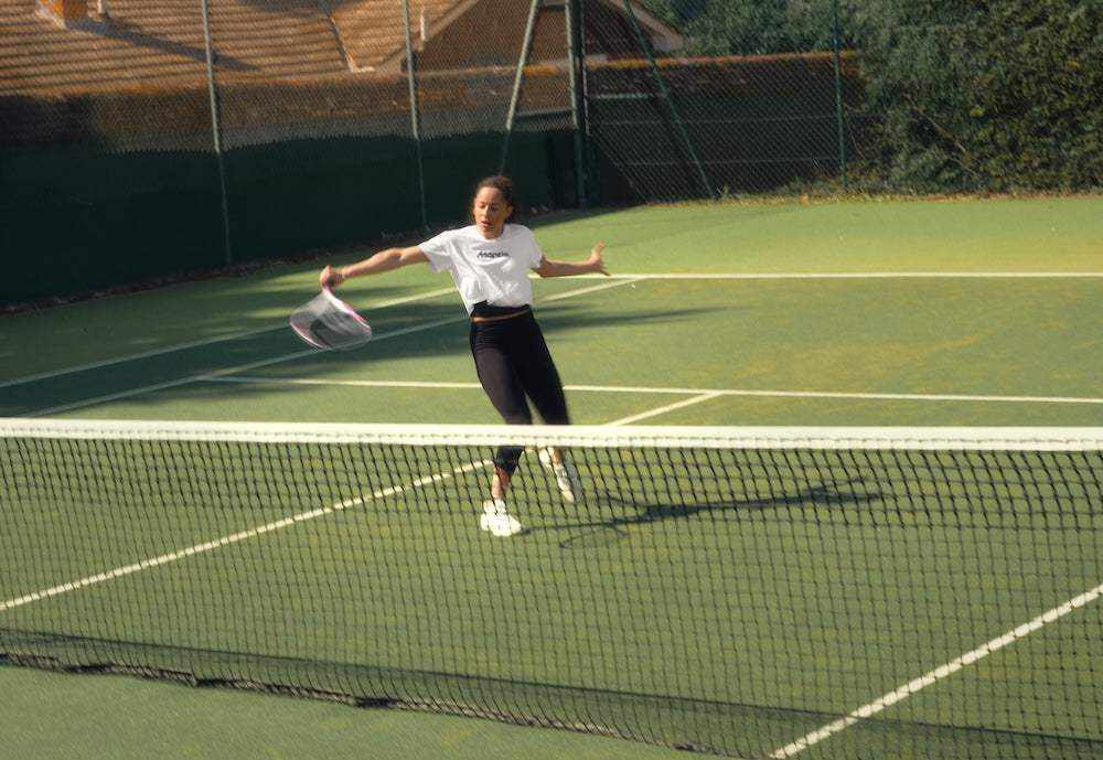 woman playing tennis with best tennis racket on outdoor court