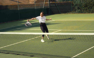 Woman playing tennis on outdoor court with a racket, showcasing best tennis rackets for women in action.