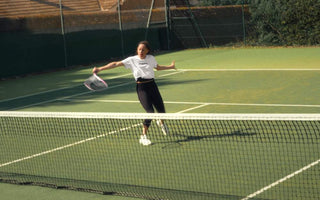 female tennis player swinging racket on outdoor tennis court during daytime