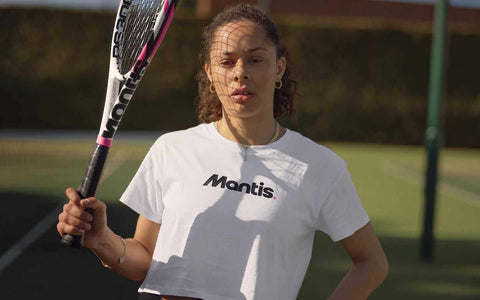 Woman holding a Mantis tennis racket on an outdoor court, demonstrating buying a tennis racket guide.