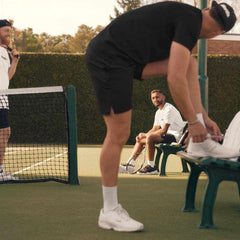 Three men preparing for a tennis session on an outdoor court, emphasizing online tennis lessons and coaching.