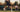 tennis player hitting powerful shot on outdoor court with coach watching holding tennis racket