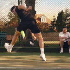 tennis player practicing hand eye coordination with coach on outdoor court