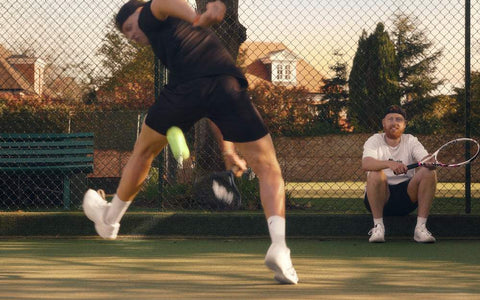tennis player practicing hand eye coordination with rapid reaction to a lime green ball on court while coach watches