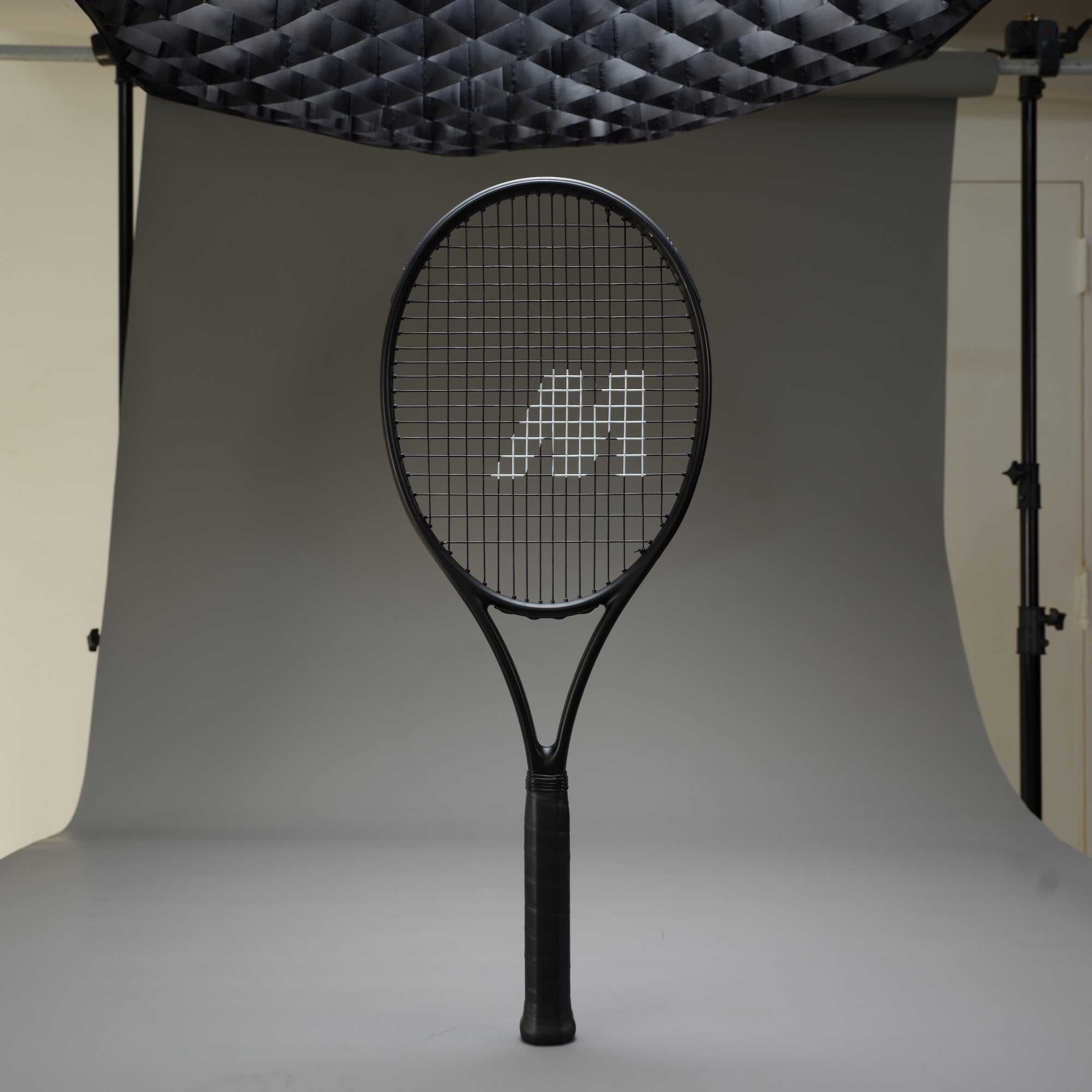 Black tennis racket with detailed stringing setup in professional studio for perfect tennis racket stringing guide