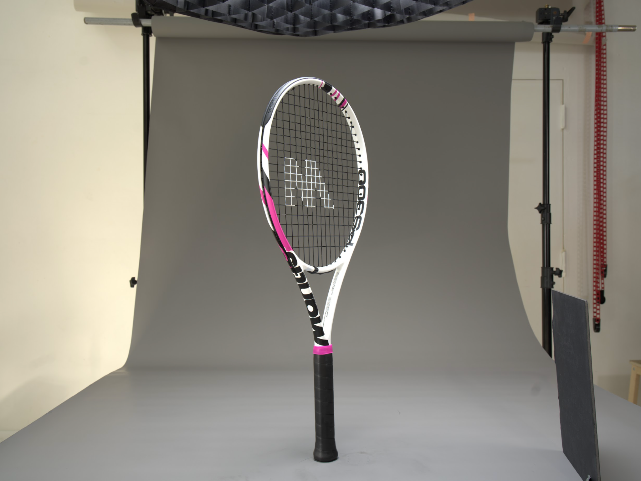 Professional studio shot of a white and pink tennis racket on grey backdrop demonstrating how to choose a tennis racket for beginners.