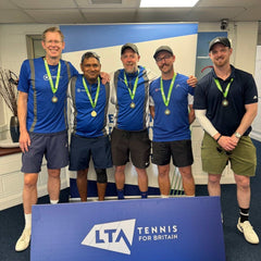 Amateur team tennis players wearing medals posing behind LTA Tennis for Britain sign